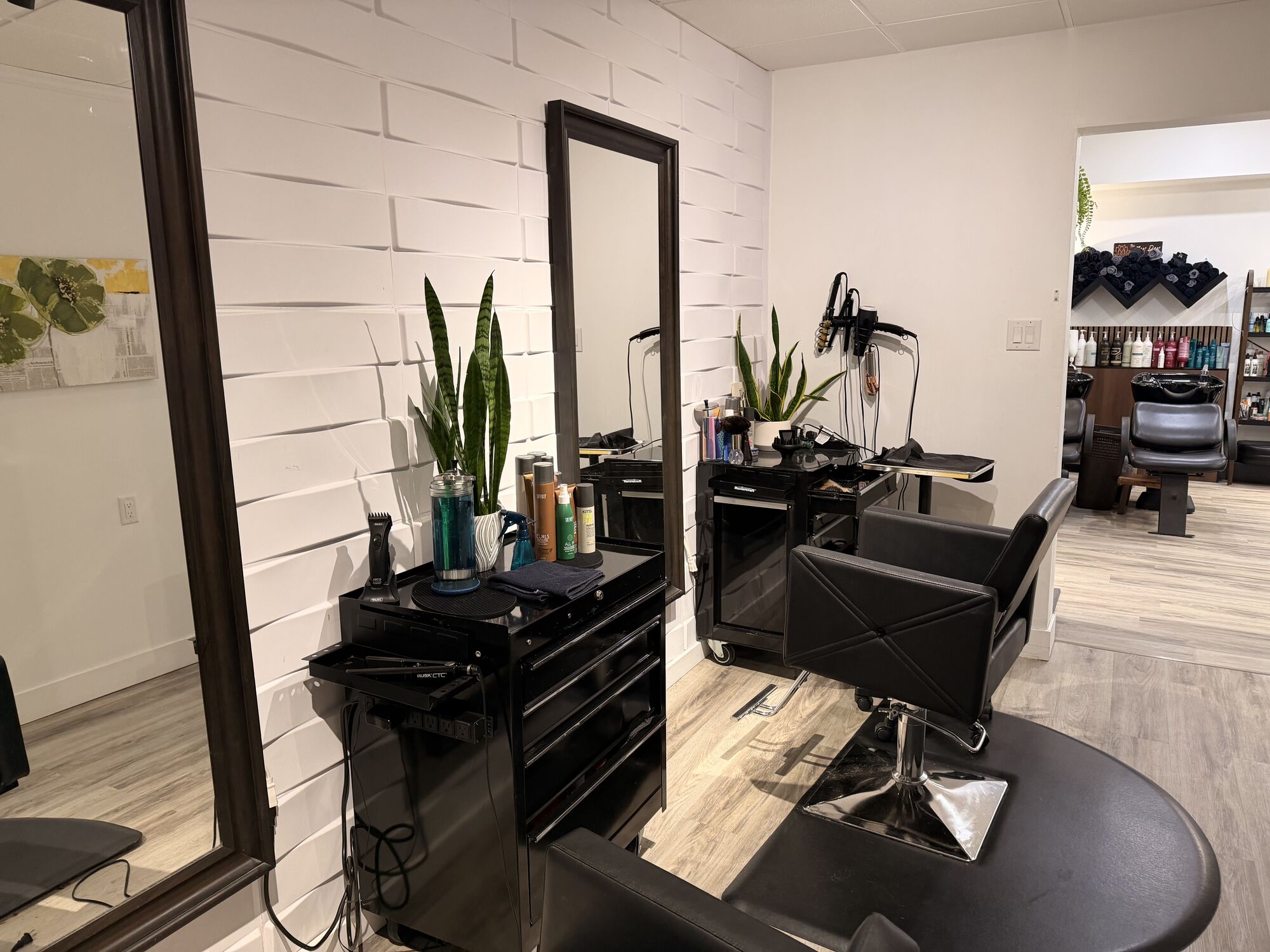 Black-framed mirror and styling station against a white textured wall